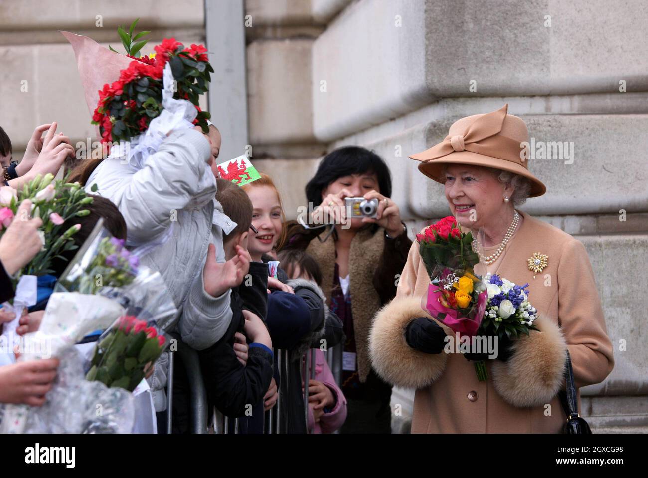 Queen Elizabeth II receives bouquets of flowers from local children when she visits the Guildhall in Swansea. Stock Photo