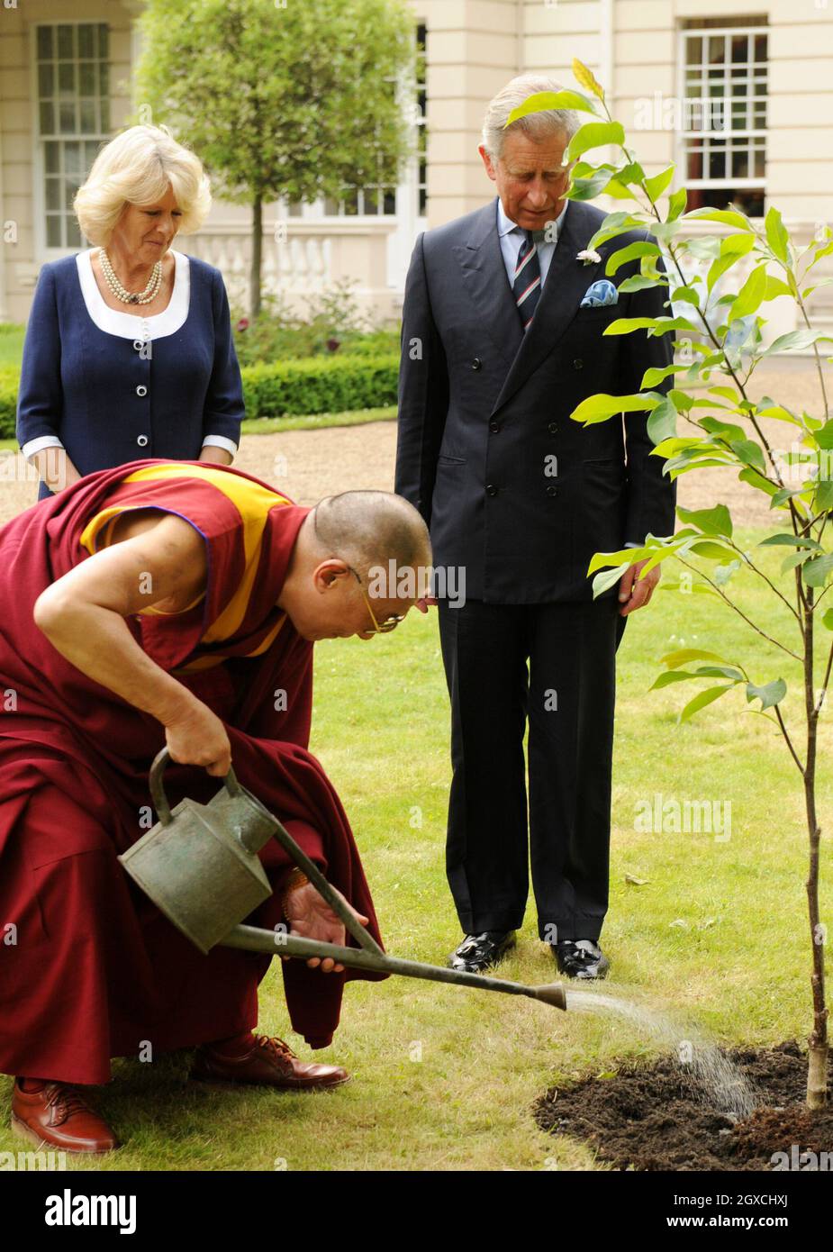 The Dalai Lama plants a tree at Clarence House watched by Prince Charles, Prince of Wales and Camilla, Duchess of Cornwall in London. Stock Photo
