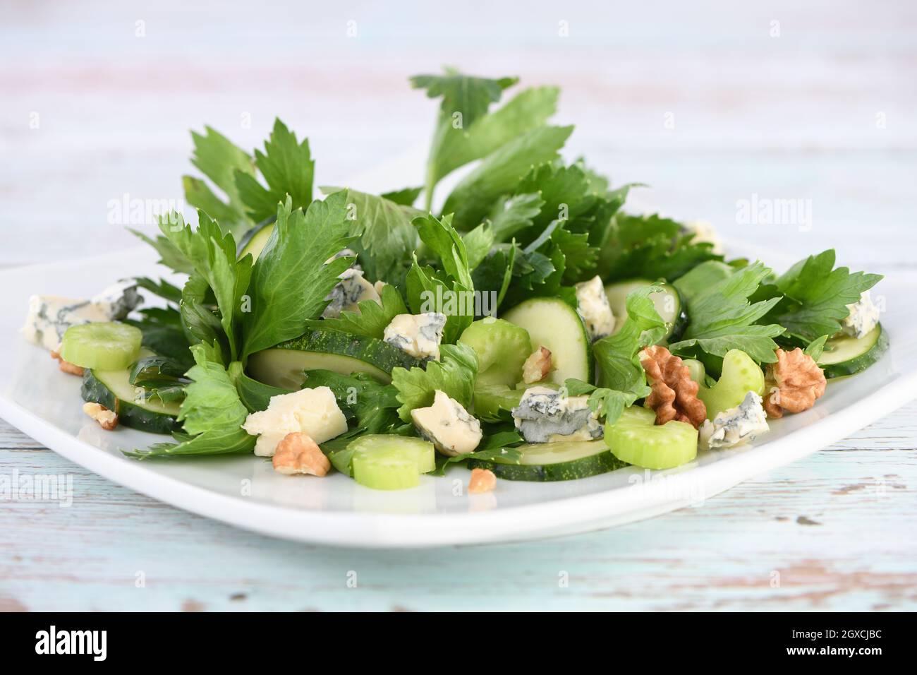 Celery leaves and stalks salad with fresh cucumber slices, blue cheese, crushed nuts. Stock Photo