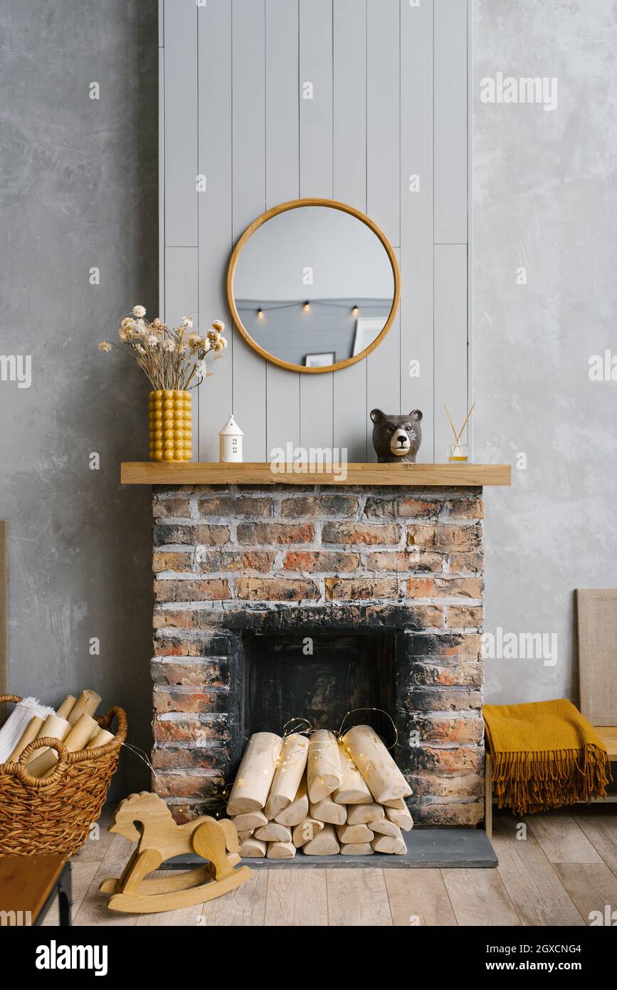 Scandinavian brick fireplace with wood and decor on it against the background of a gray wall of a country house Stock Photo