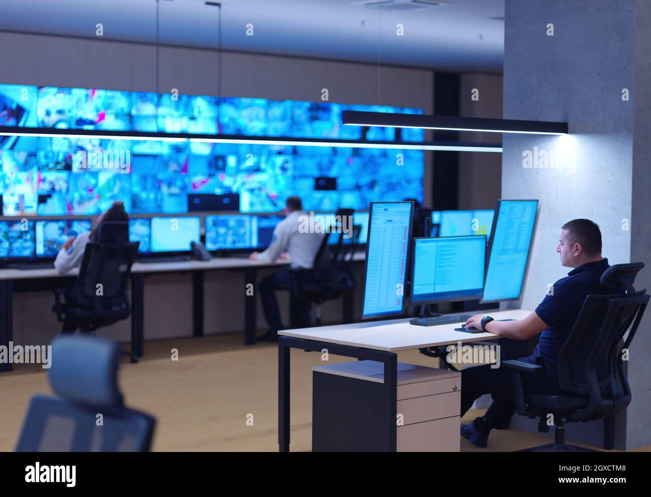 Male security operator working in a data system control room offices