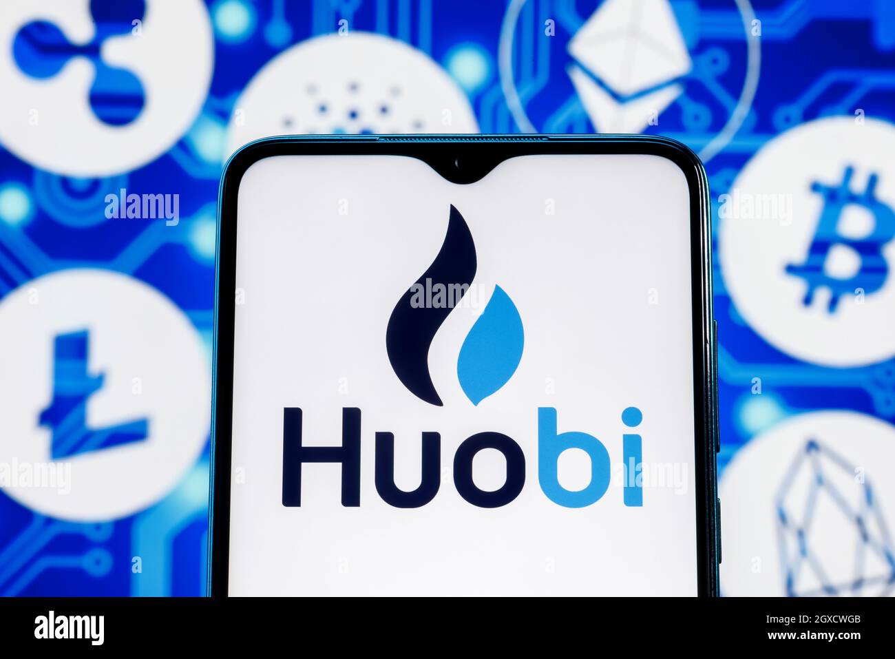 Huobi is a cryptocurrency exchange. Huobi logo on smartphone screen against the background of the main cryptocurrencies. Stock Photo
