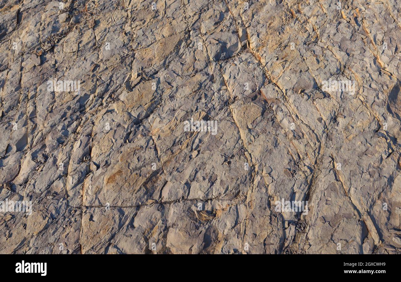 Texture, background layers and cracks in sedimentary rock on cliff face. Rock slate in the mountain. Seamless abstract background. Cracks and layers o Stock Photo