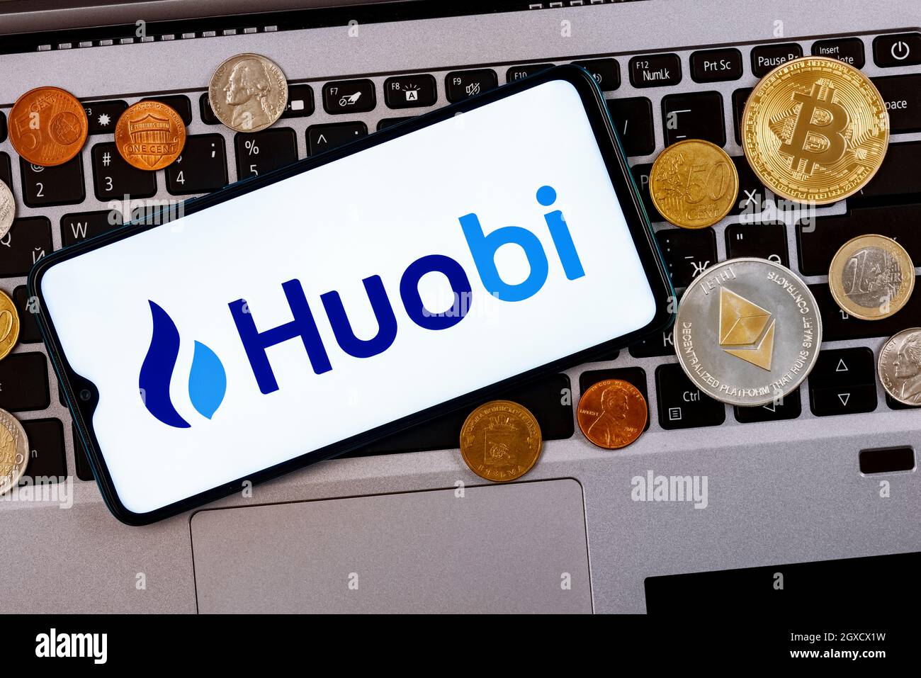 Huobi is a cryptocurrency exchange. A smartphone with the Huobi logo metal  coins, bitcoin, ethereum on a laptop keyboard Stock Photo - Alamy