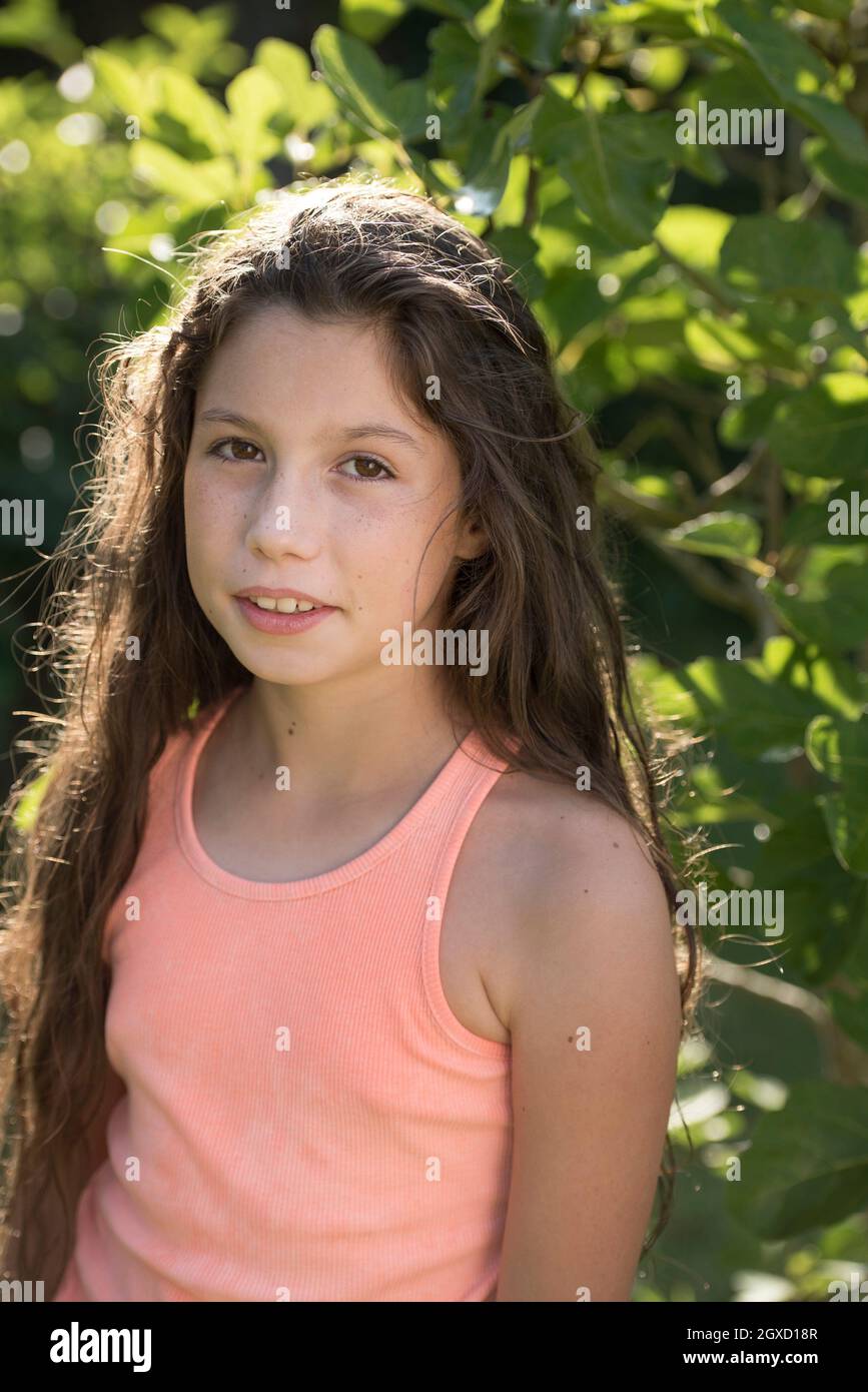 Young girl in denim shorts and pink-orange tank top with wet hair posing in  front of a fig tree, France Stock Photo - Alamy