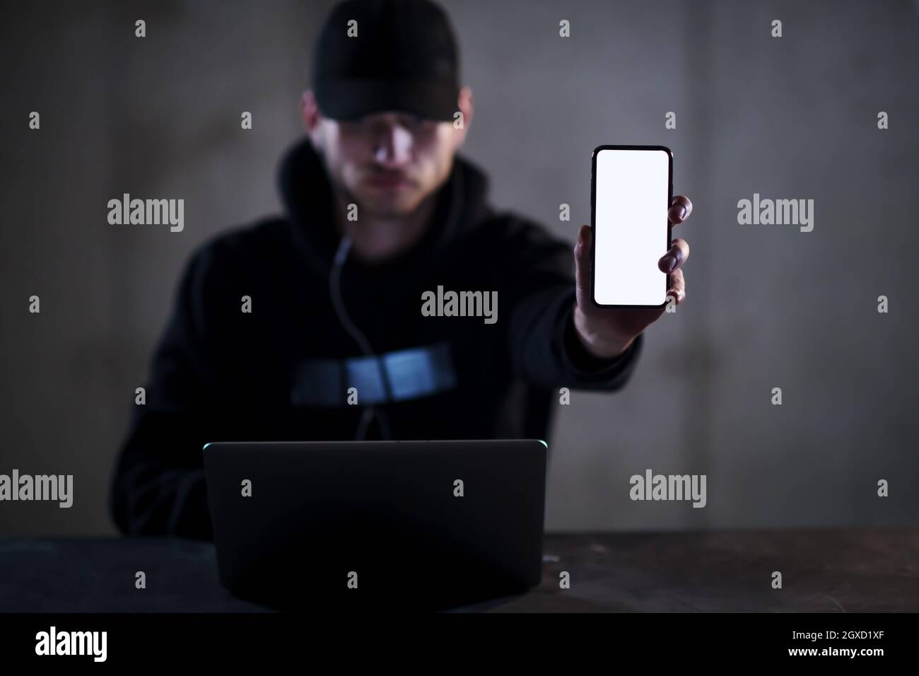 Young talented criminal hacker using laptop computer and showing the ...