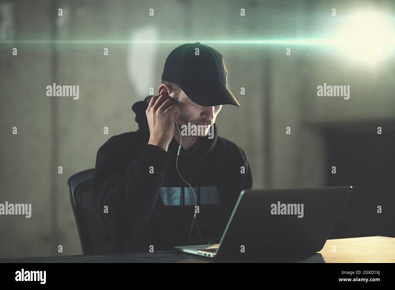 Young talented hacker using laptop computer while working in dark ...