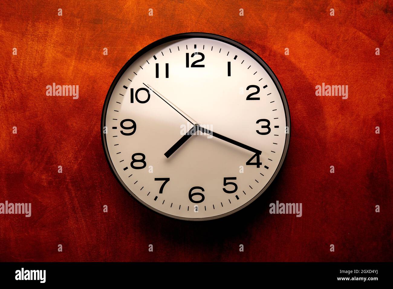 Round shaped minimalistic clock with numbers and arrows on colorful red ...