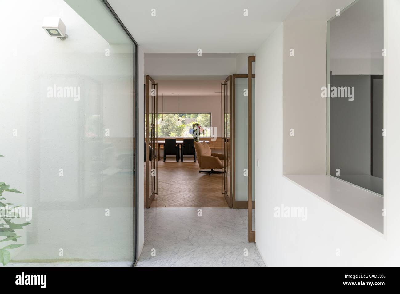 Visual Reference: Narrow Hallway With Glass Walls Leading To Spacious Living Room