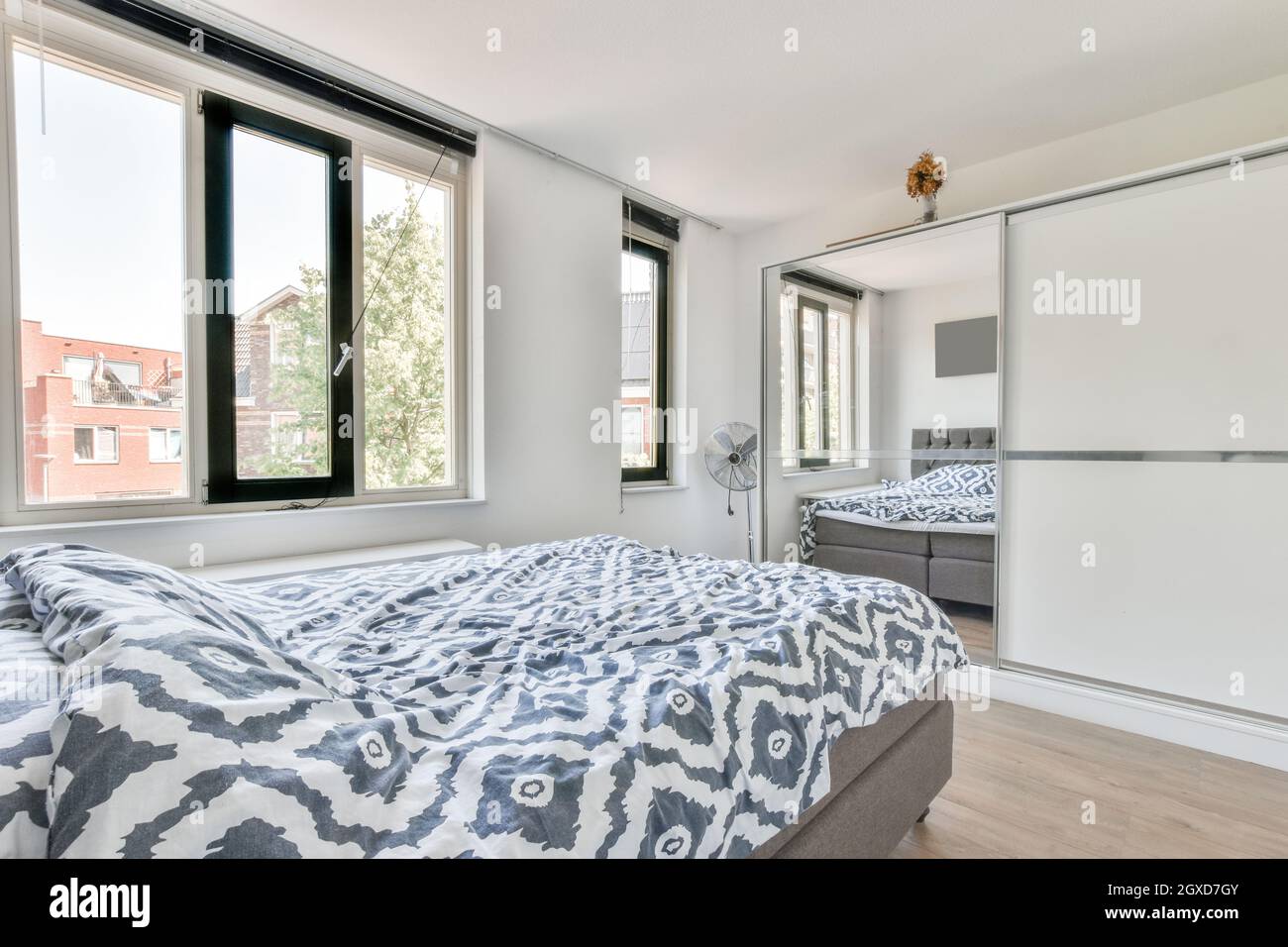 Interior of light bedroom with large wardrobe with mirror and