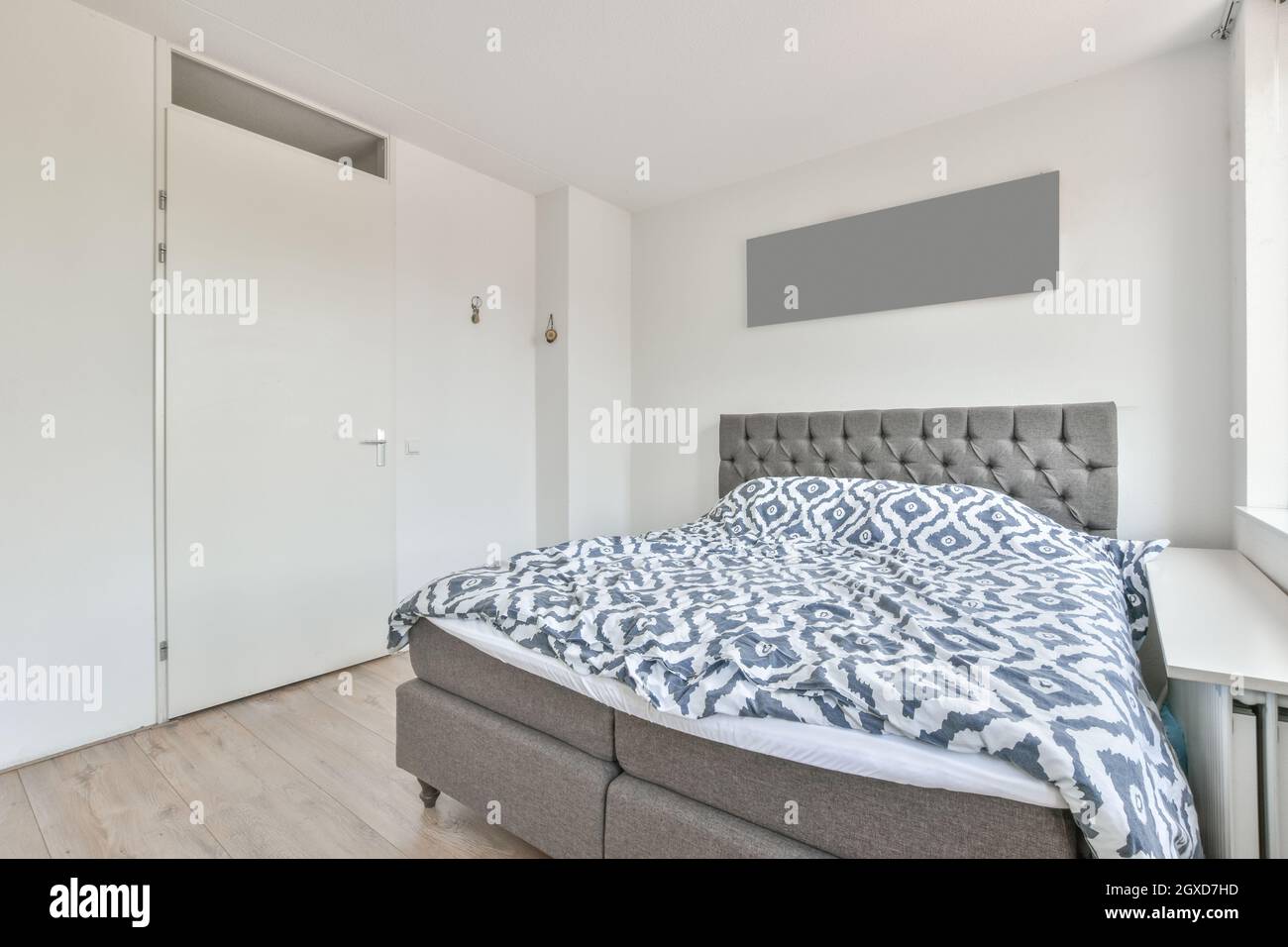 Interior of light bedroom with large comfortable bed with stylish linen