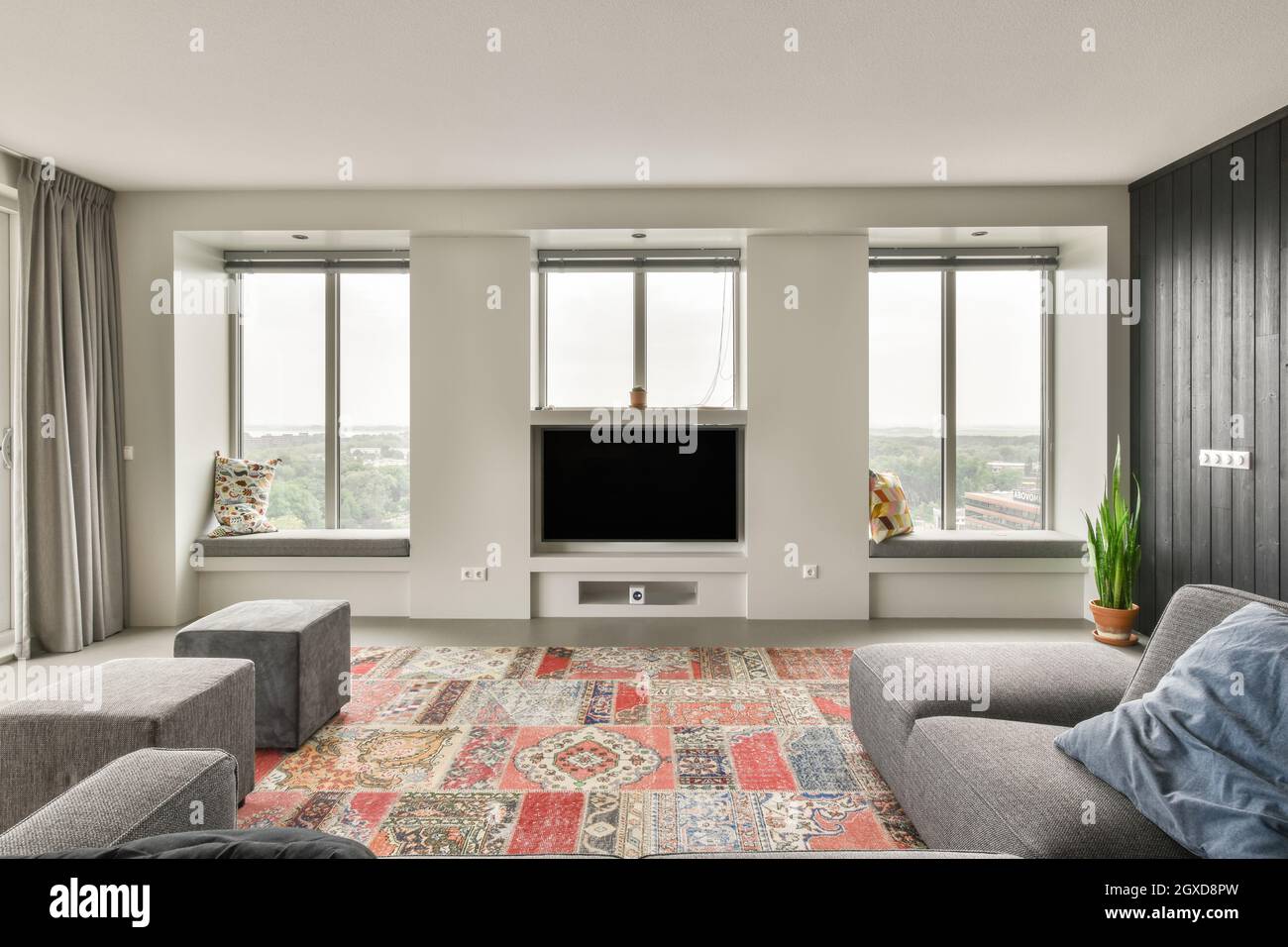 Modern living room with TV and windows placed opposite soft sofa and