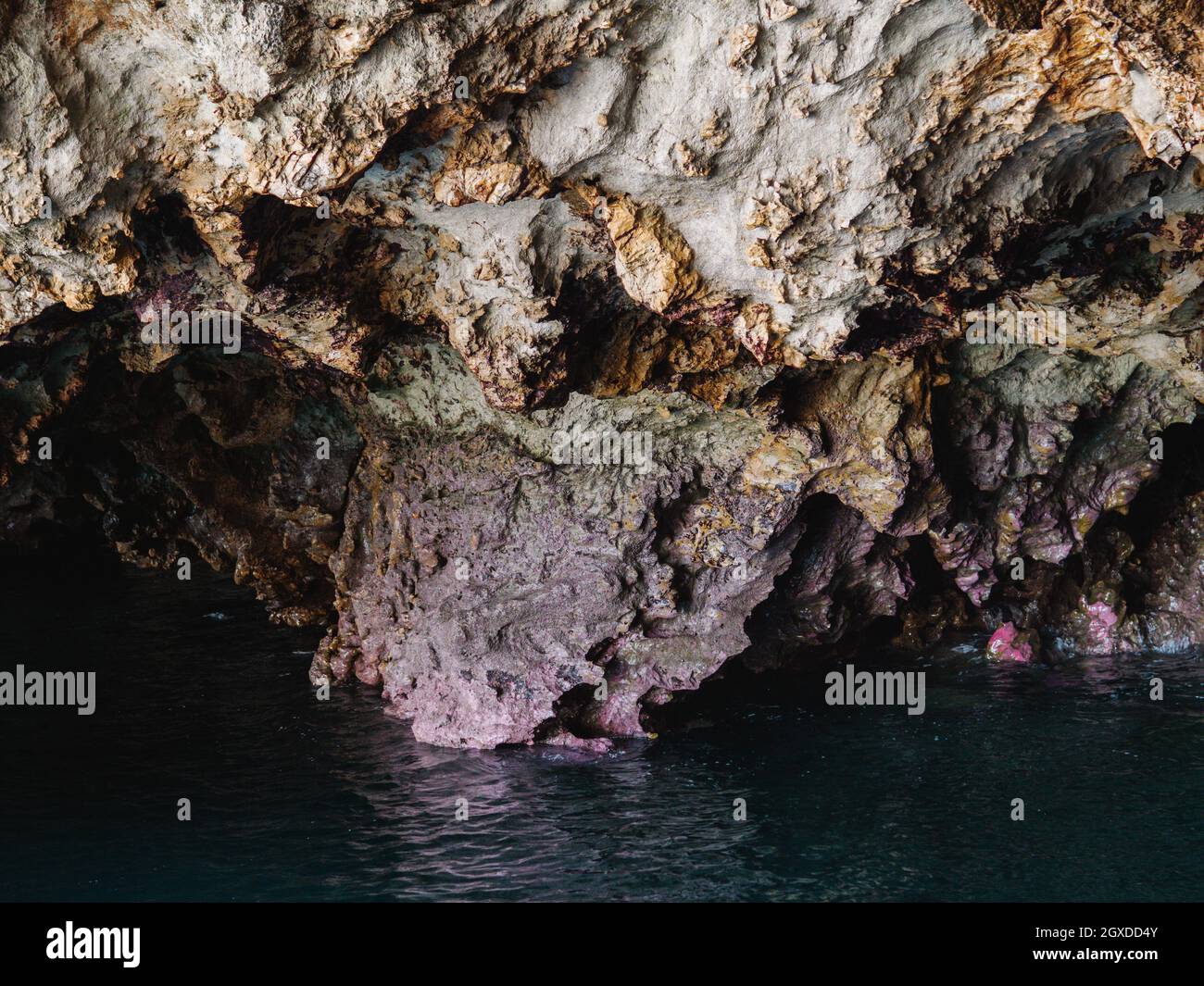 Transparent clear rippling seawater flowing through rocky rough cave ...