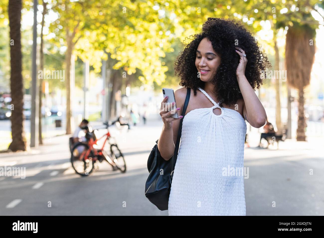Positive African American female with Afro hairstyle touching tummy while browsing on cellphone on the street with green trees Stock Photo - Alamy Positive African American female with Afro hairstyle touching tummy while browsing on cellphone on the street with green trees Stock Photo - Alamy
