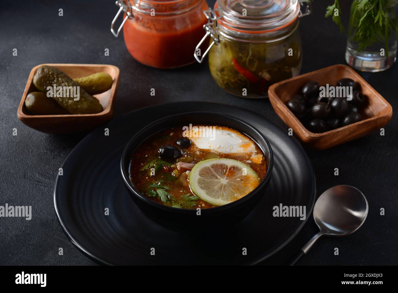 Russian traditional soup 'Solyanka' with meat, sausages, salted cucumbers and olives.Soup in wooden bowl rustic style Stock Photo