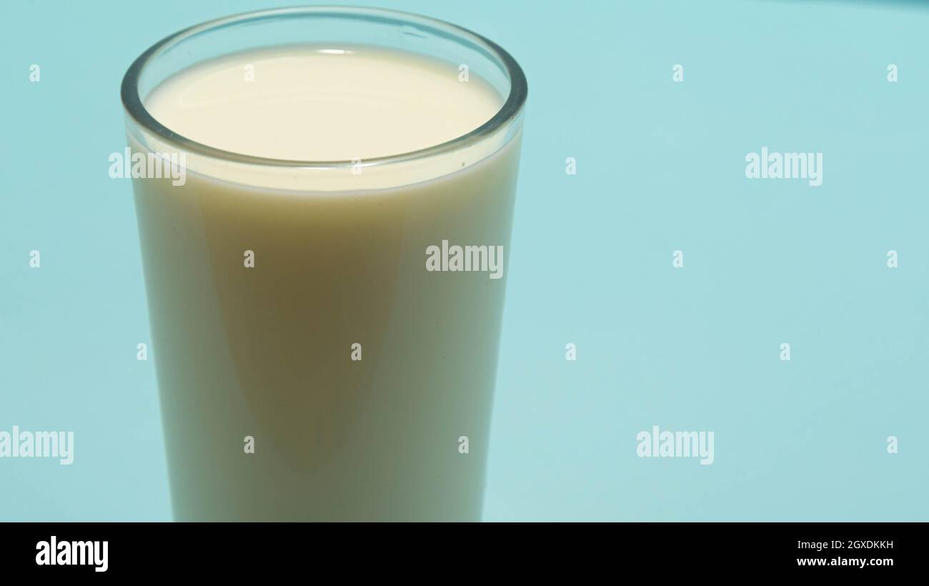 Glass cup served with milk on the blue background. Bone health food. Milk is one of the best sources of calcium available. Therefore, this food is ess Stock Photo
