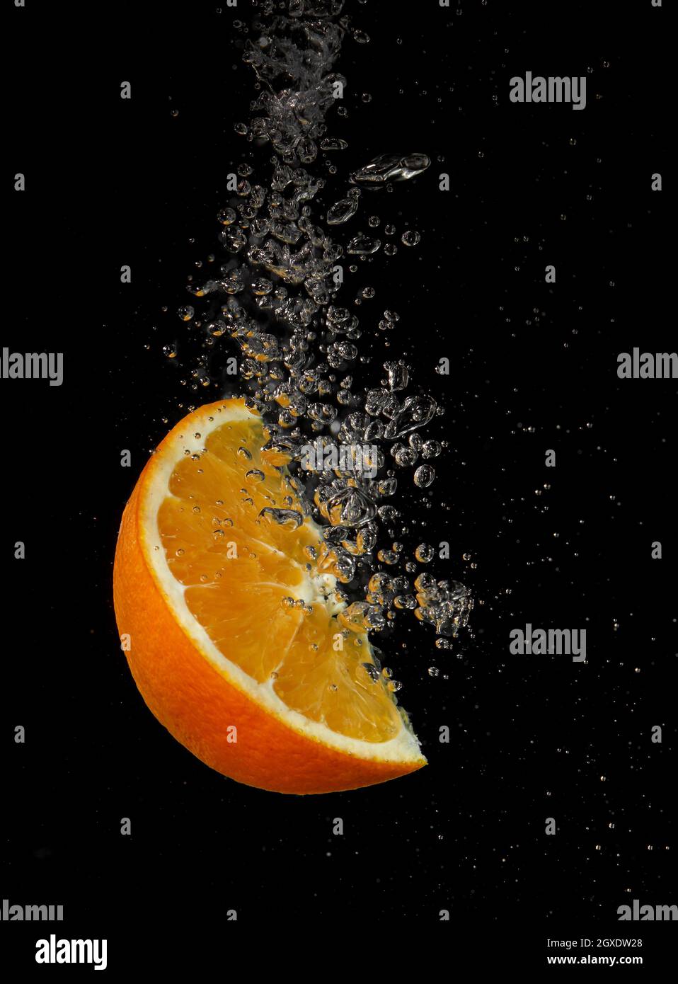 Orange splashing in water on a black background Stock Photo - Alamy