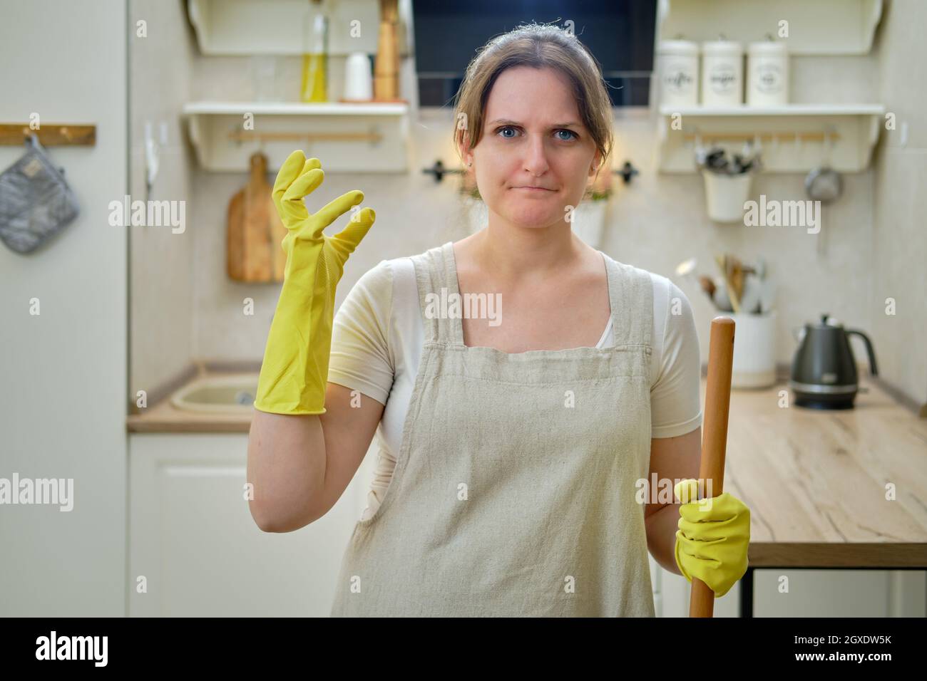Angry woman glares at the camera while cleaning in the home kitchen Stock Photo