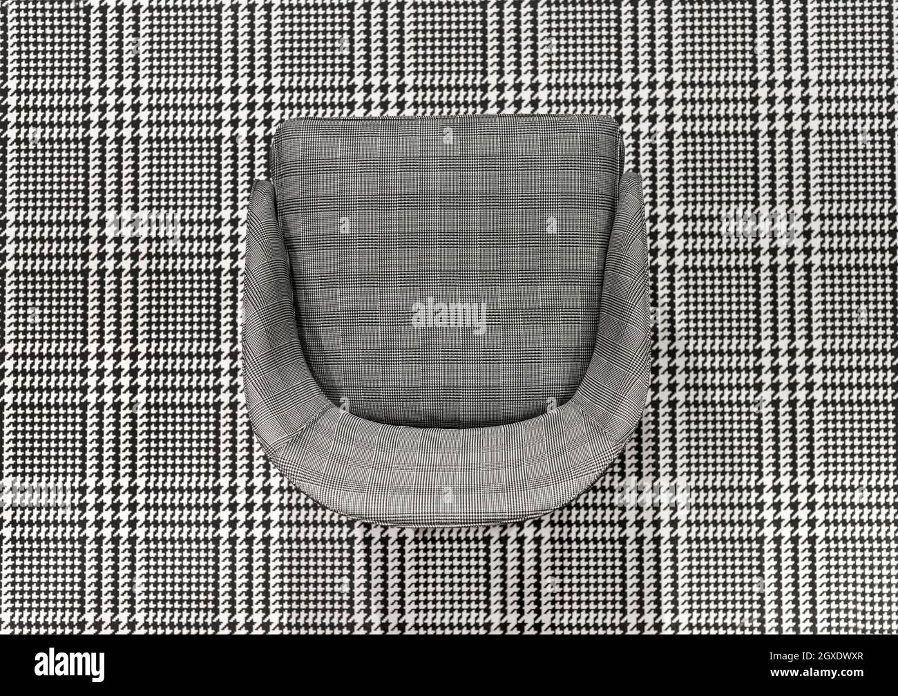 Upholstered checked pattern chair juxtaposed on matching black and white woven plaid textile in a top down view for high contrast effect for design Stock Photo