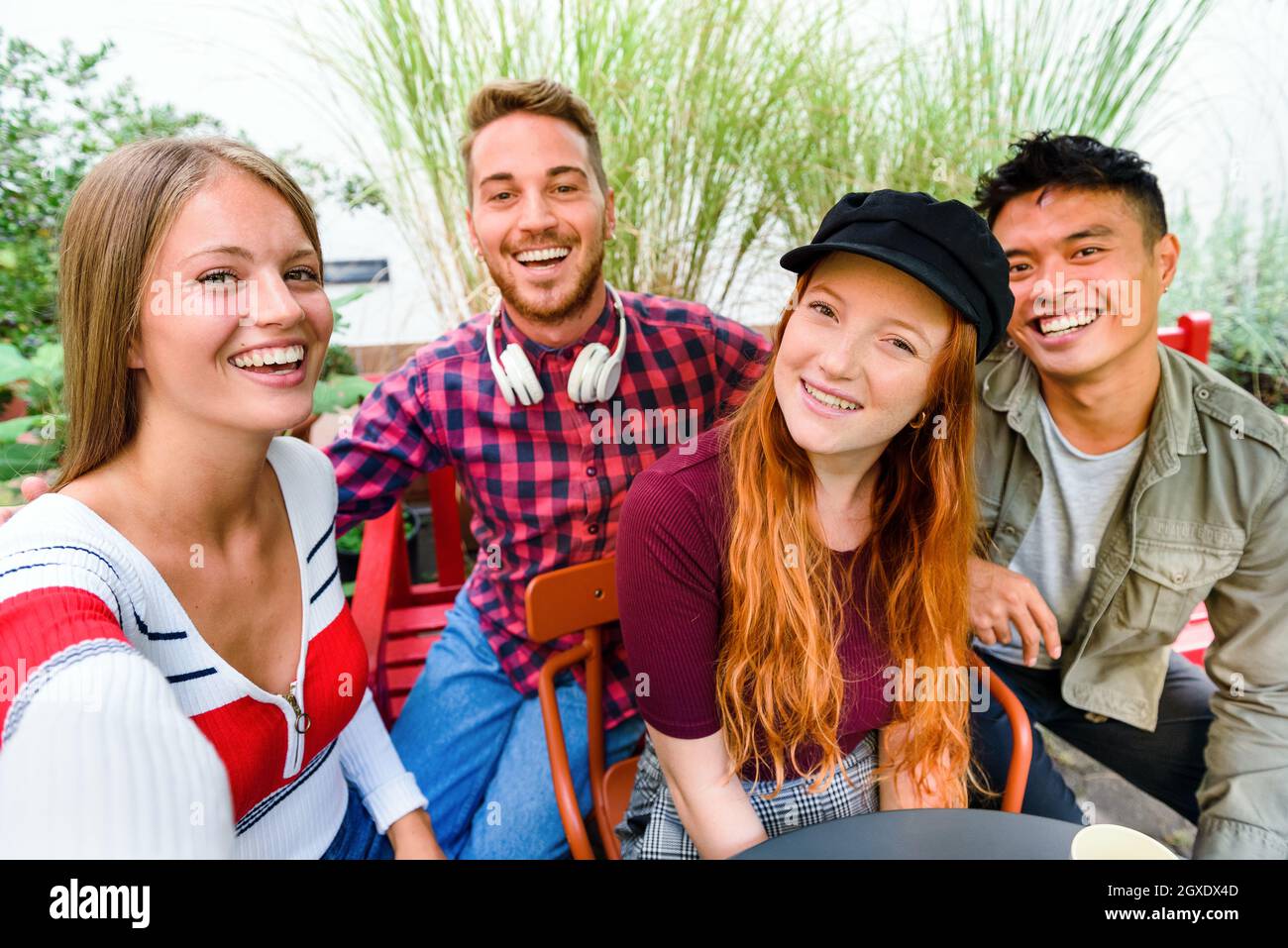 Happy laughing diverse group of young friends taking a selfie together grouped around a table on an outdoor patio Stock Photo