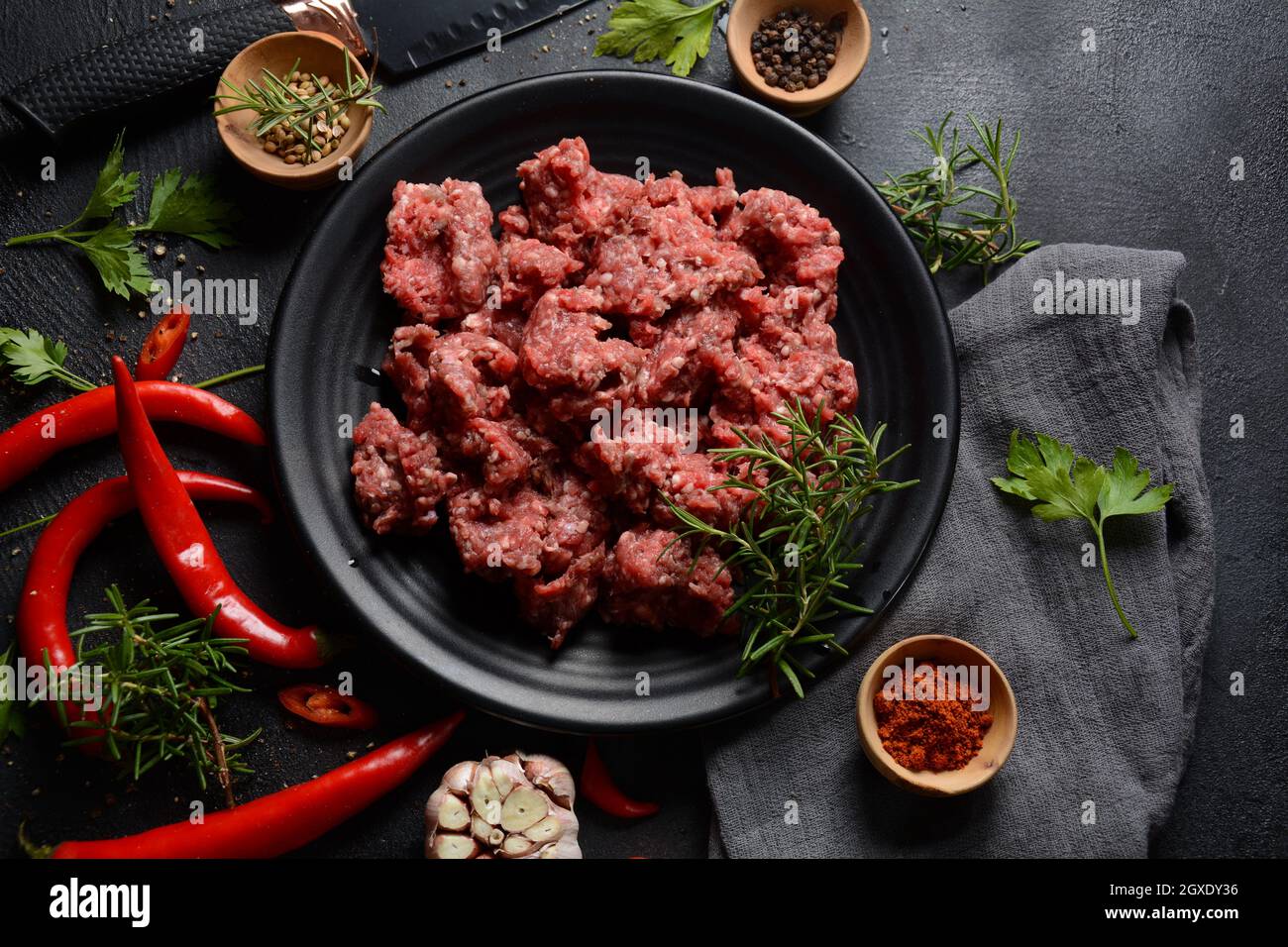 Minced beef. Ground meat with ingredients for cooking on black