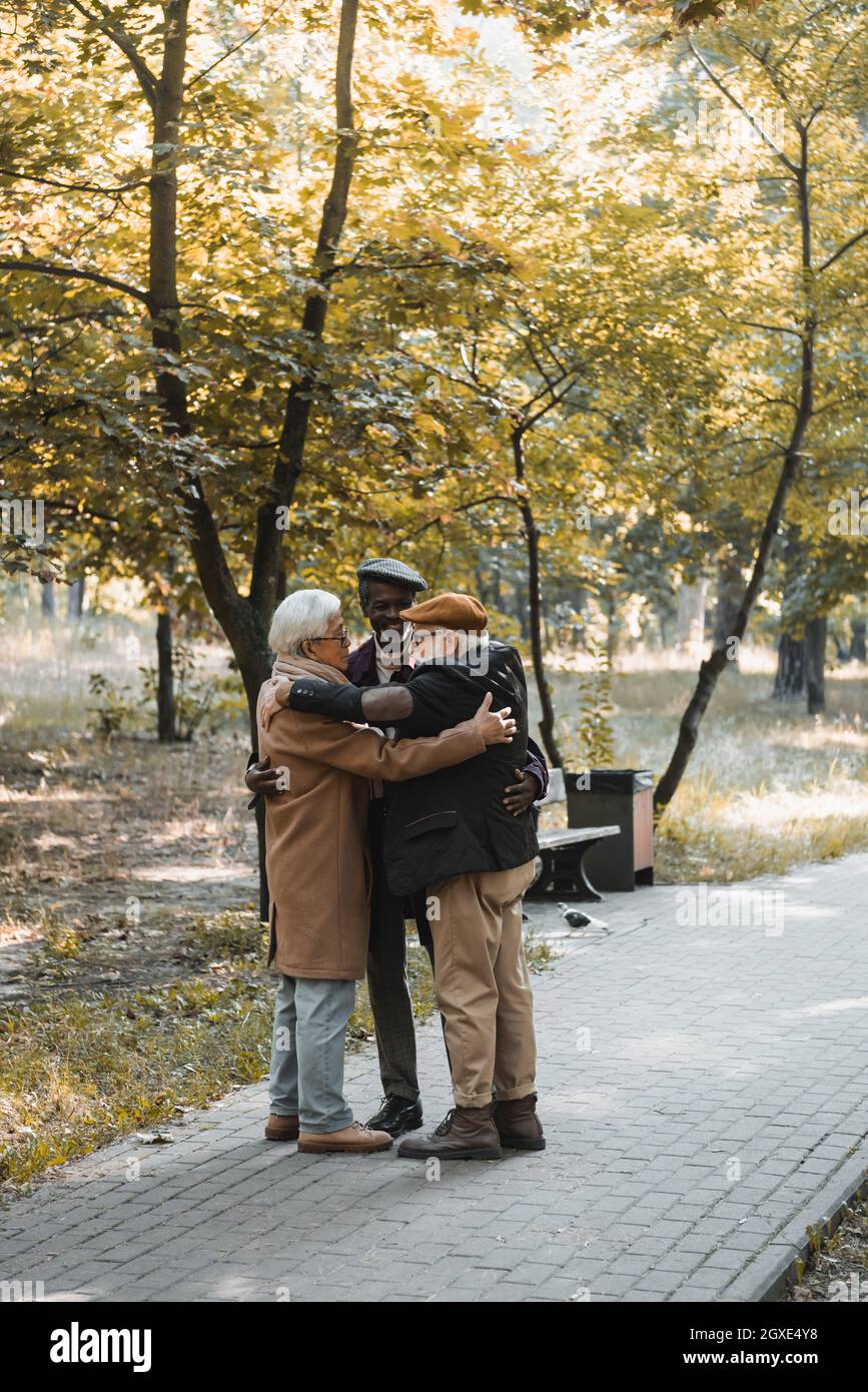 Positive multicultural friends hugging in autumn park Stock Photo