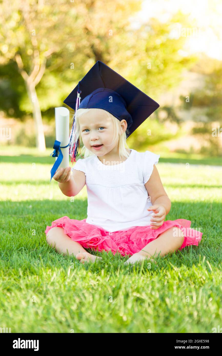 Cute Little Girl In Grass Wearing Graduation Cap Holding Diploma With Ribbon Stock Photo Alamy