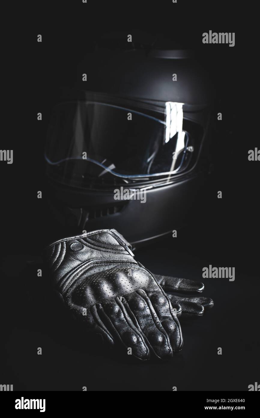 Black leather motorcycle gloves and helmet on a black background. Stock Photo