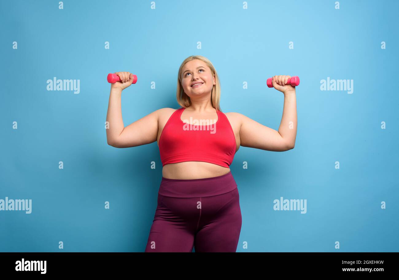 Fat girl does gym at home. satisfied expression. Cyan background Stock  Photo - Alamy