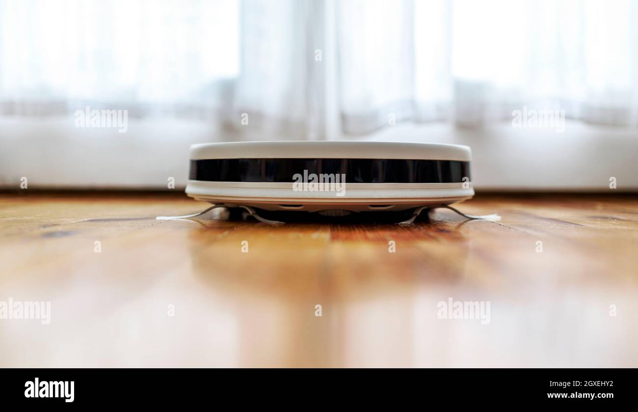 Robot vacuum cleaner and mop cleaning living room floor closeup. Modern
