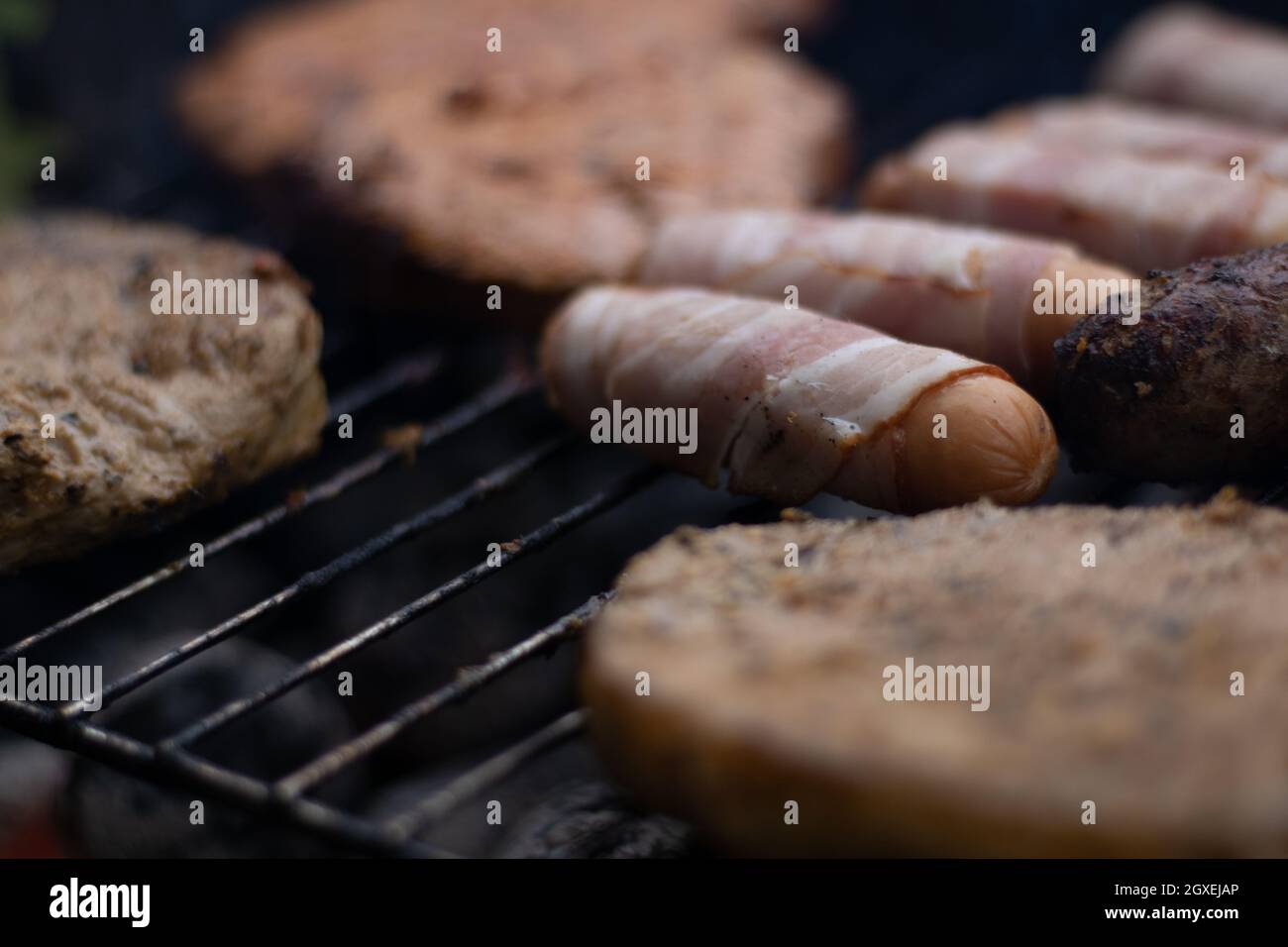 Sausages and pieces of meat laying on a grill at a Barbeque Stock Photo