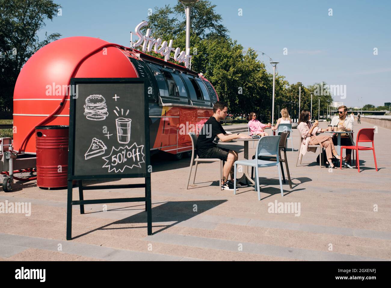 Blackboard with discount announcement against outdoor cafe and street food truck Stock Photo