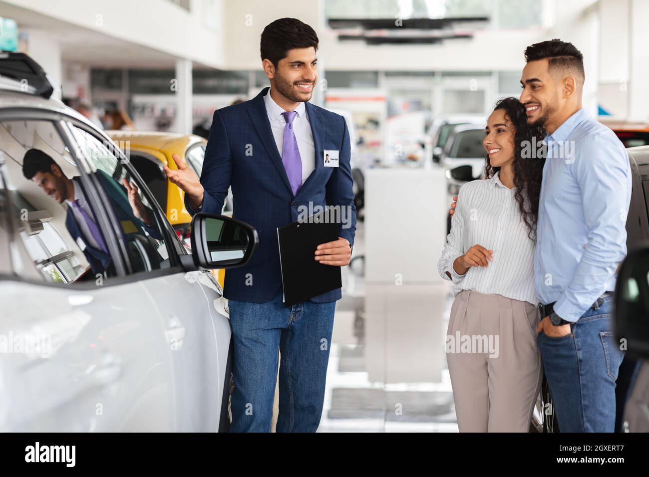 Smiling middle-eastern couple looking at white car Stock Photo
