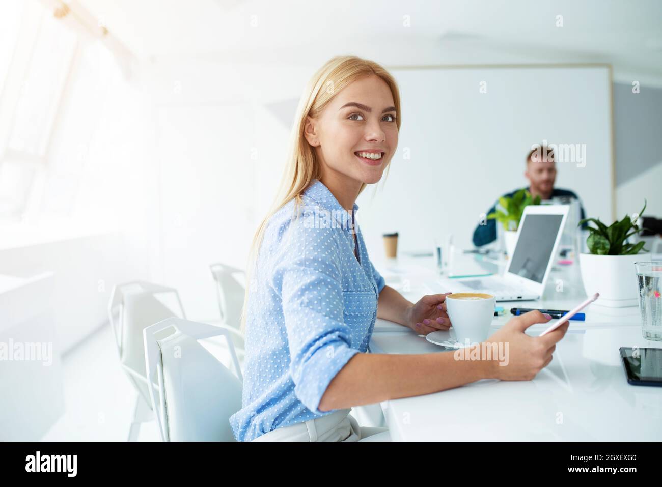 Happy woman in office takes a coffee break during her work Stock Photo ...