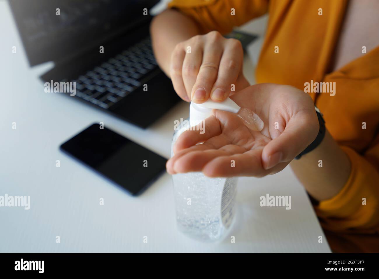 Hand sanitizer. Close up of business woman hands sanitizing with alcohol gel in the office. Stock Photo
