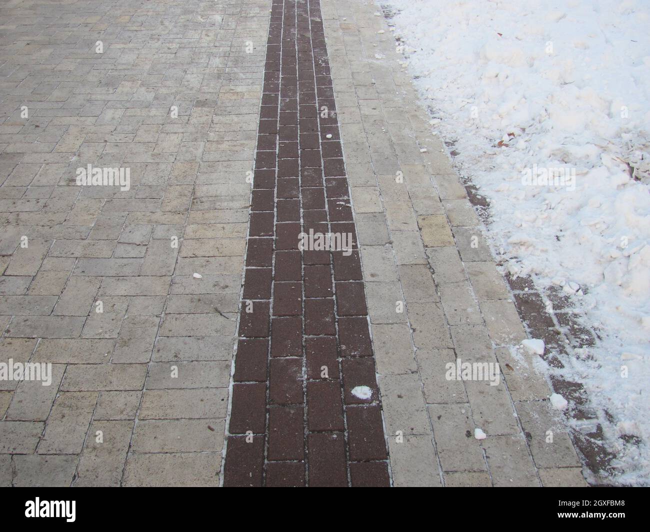 A tiled path in a snow-covered park Stock Photo