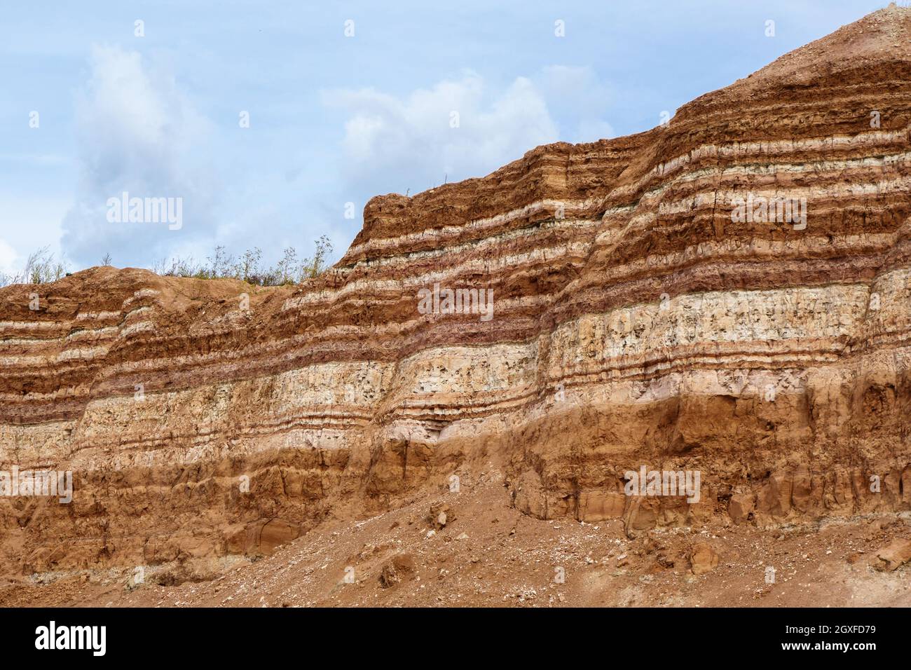 Earth wall in industrial quarry with open-pit mining. It can be seen very clearly underground layers of useful minerals Stock Photo