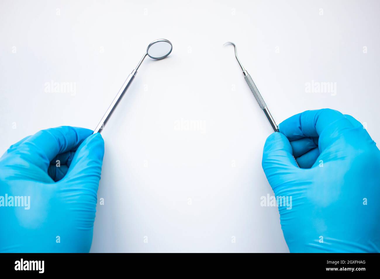 Dentist mirror and probe in hands isolated on white. Professional