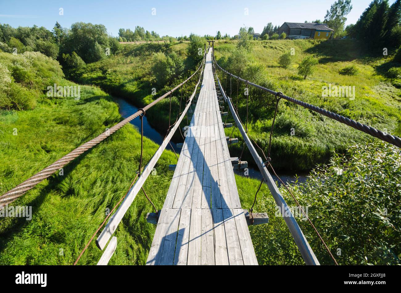 Wooden suspension bridge over a small river Stock Photo - Alamy