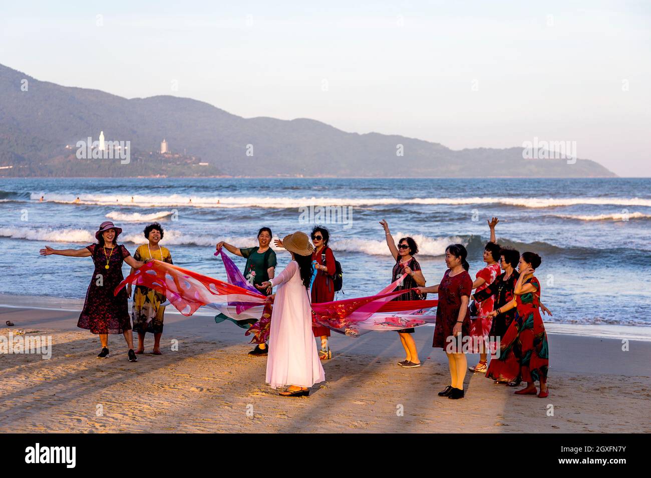 A group of women wearing dresses and playing a game with ribbons at My Khe Beach, Da nang. Stock Photo