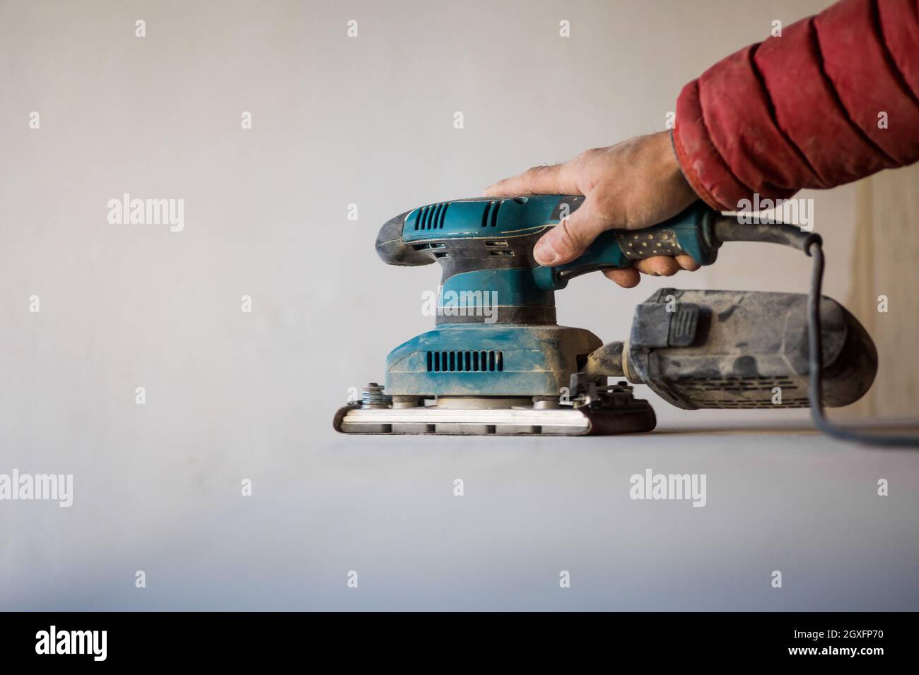 Man sanding wood plank using electric sand machine. Stock Photo