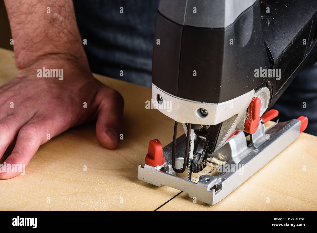 Man with electric jig saw cutting plywood Stock Photo
