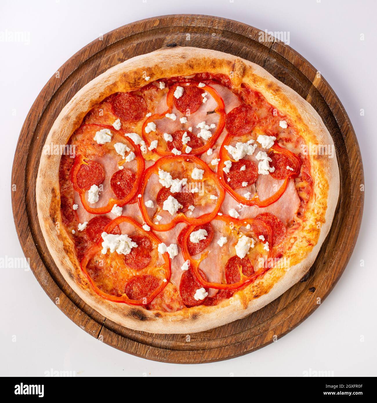 Top view of hot pizza on a wooden stand. Pizza 4 seasons . Made on tomatoes, with spicy salami, tender ham, and complements with shades of sweet peppe Stock Photo