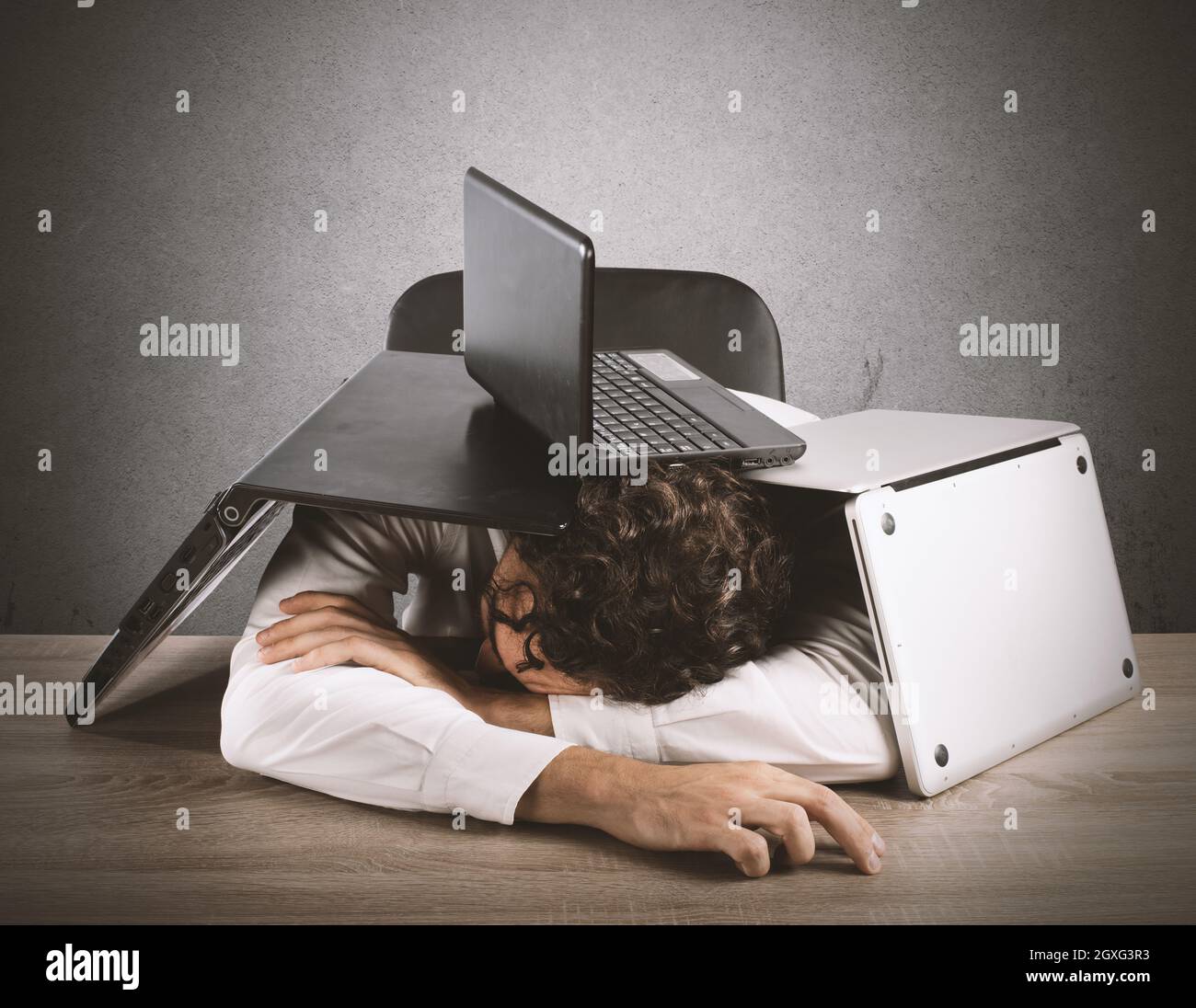 Tired businessman sleeping under a pile of computers Stock Photo Alamy