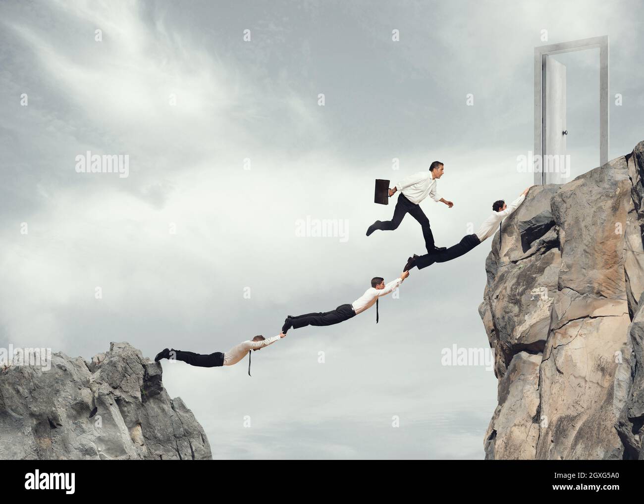 Businessmen working together to form a bridge between two mountains to reach a door. concept of ambition in business Stock Photo