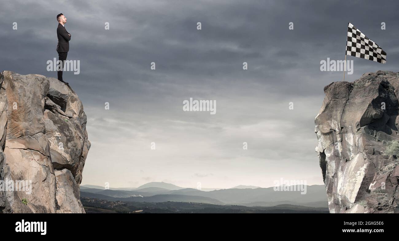 Man looks at a flag on the other side of the mountain. Business concept of businessman overcome the problems Stock Photo