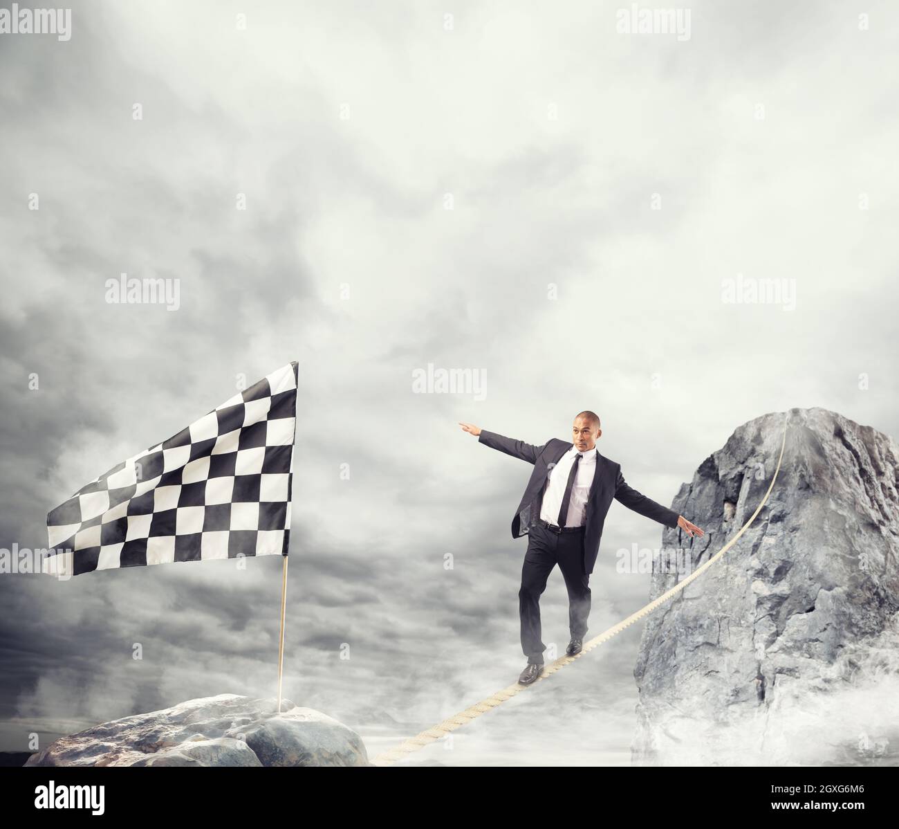Business concept of businessman who overcome the problems reaching the finish line on a rope Stock Photo