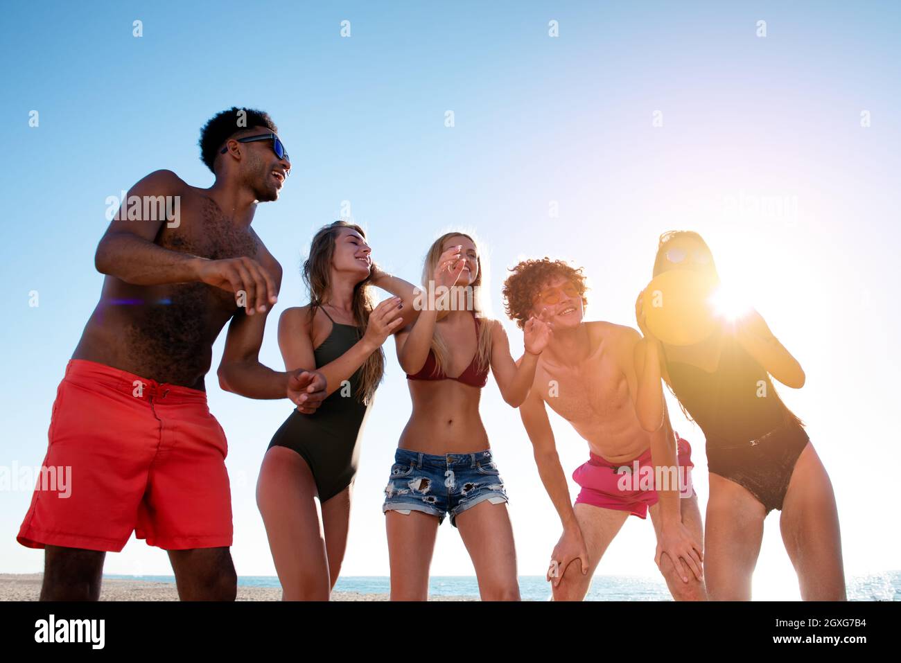 Group of happy friends playing at beach volley at the beach Stock Photo