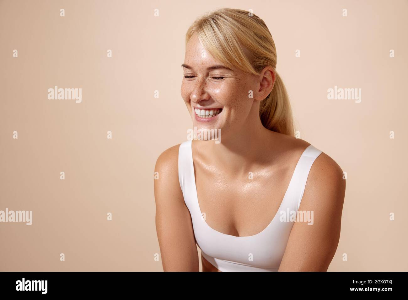 Portrait of a laughing woman with perfect skin and freckles against pastel background Stock Photo