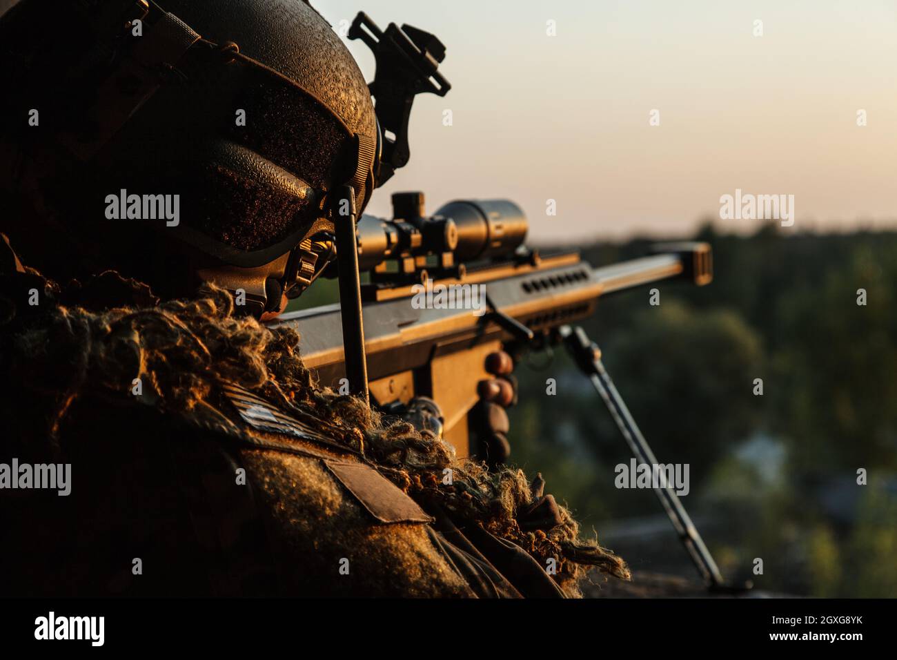 Special forces sniper with large-caliber rifle seeking and killing enemy. Back view sunset sky background Stock Photo